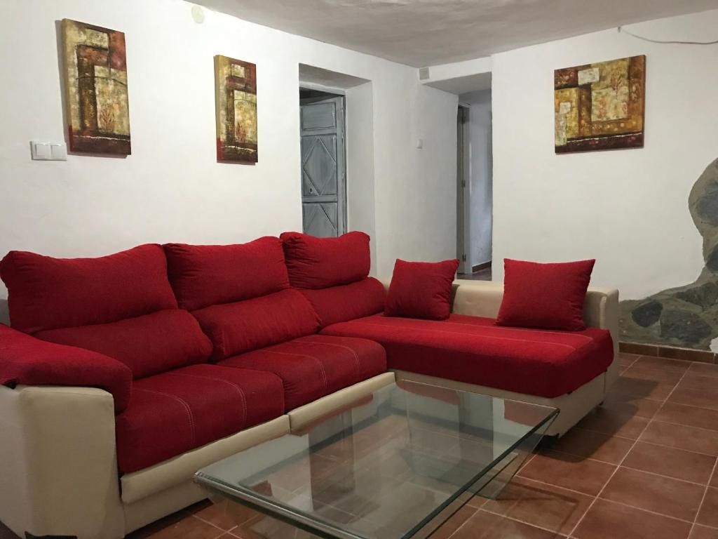BenalauríaCasa Rural Pimentel的客厅配有红色的沙发和玻璃桌