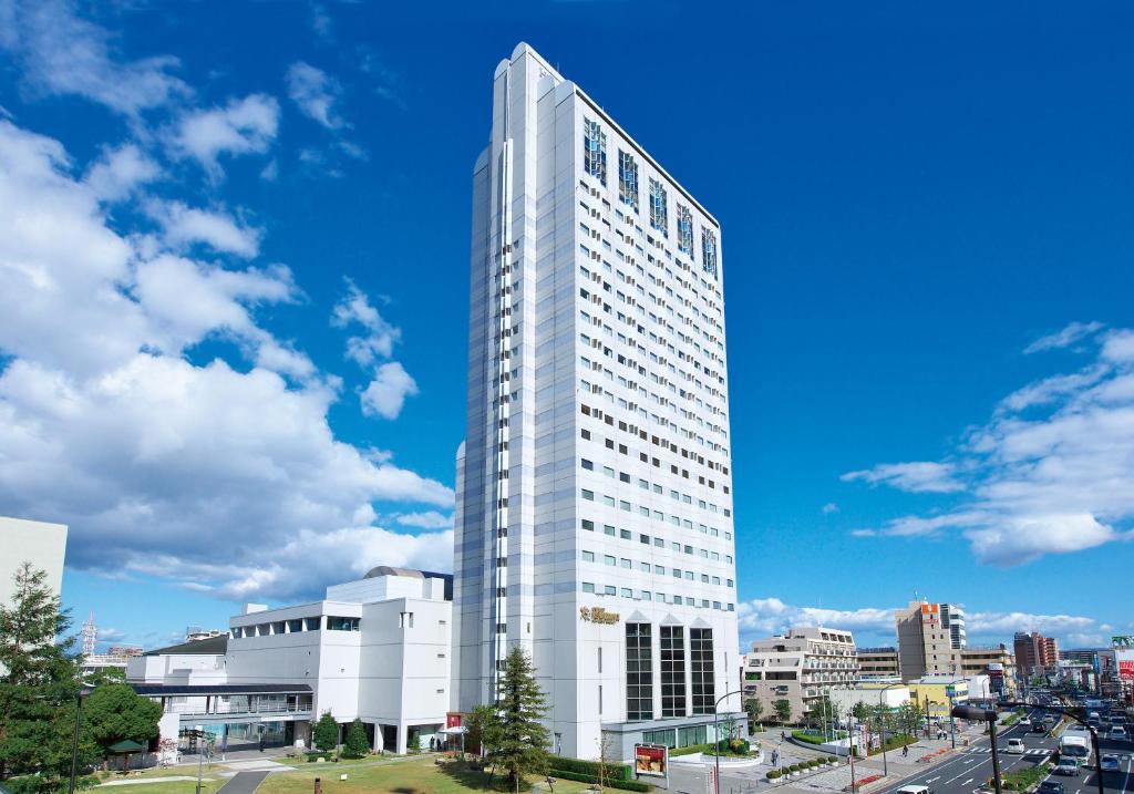 尼崎市Miyako Hotel Amagasaki的蓝色天空城市中高大的白色建筑