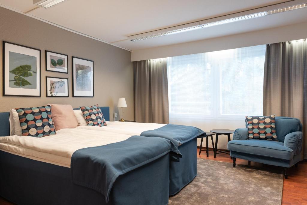 塞伊奈约基索桑佩萨酒店的一间卧室配有一张大床和一张蓝色椅子