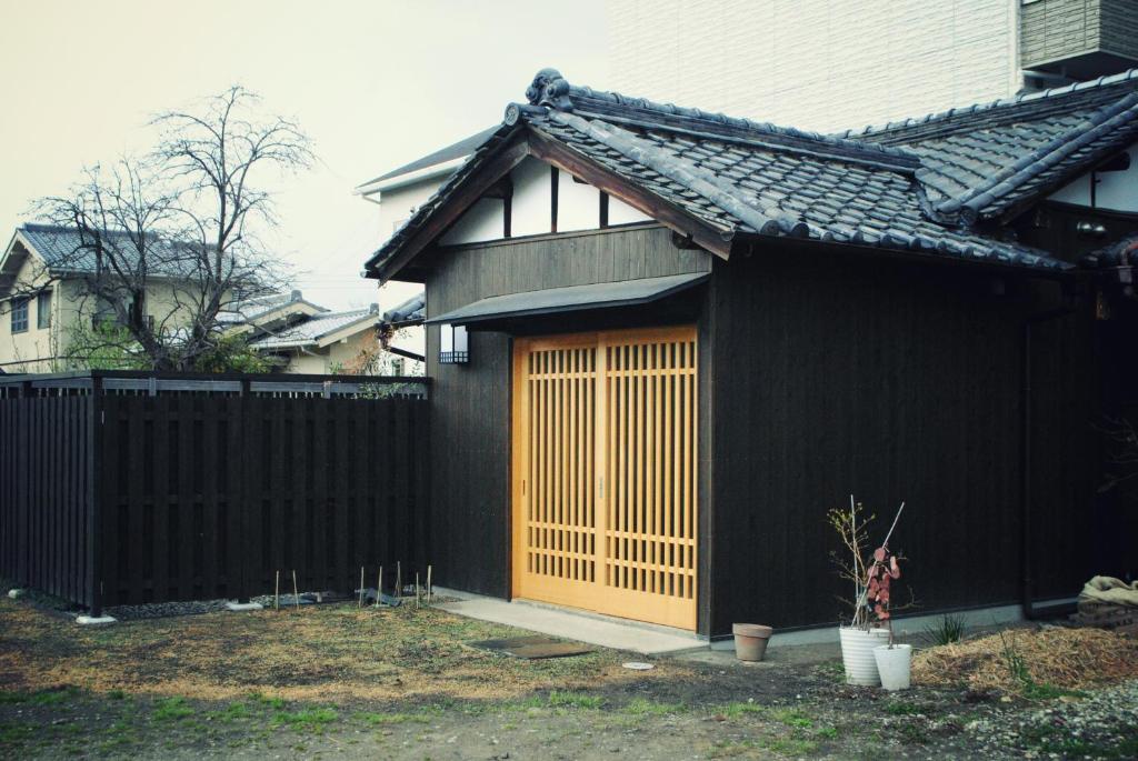 奈良NARAigoto EENA HOUSE的一间铁栅栏旁的黑色房子,木门旁边