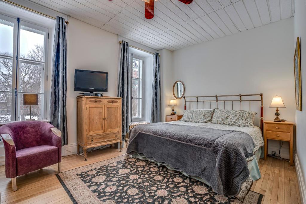 魁北克市苏尔乐凯普庄园酒店的一间卧室配有一张床、一台电视和一把椅子