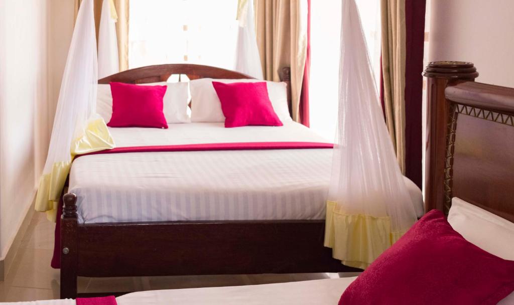 恩德培Sienna Beach Hotel Entebbe的一间卧室配有带粉红色枕头的床和窗户。