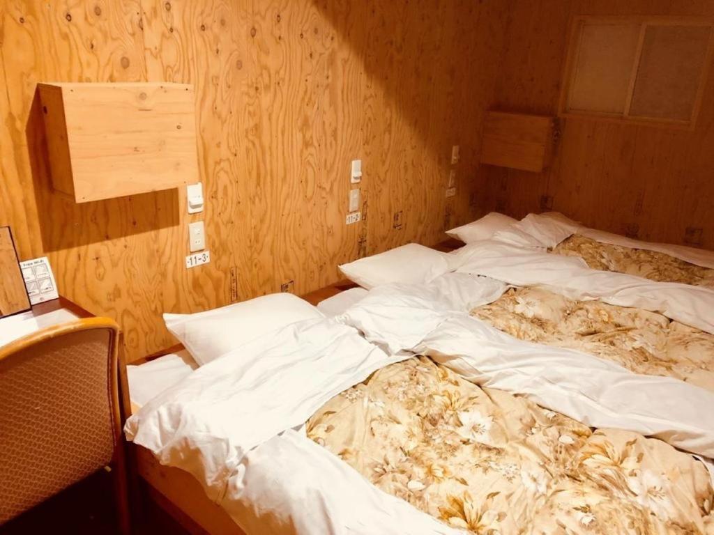 小樽Guesthouse Otaru Wanokaze triple room / Vacation STAY 32203的木墙客房的两张未铺床