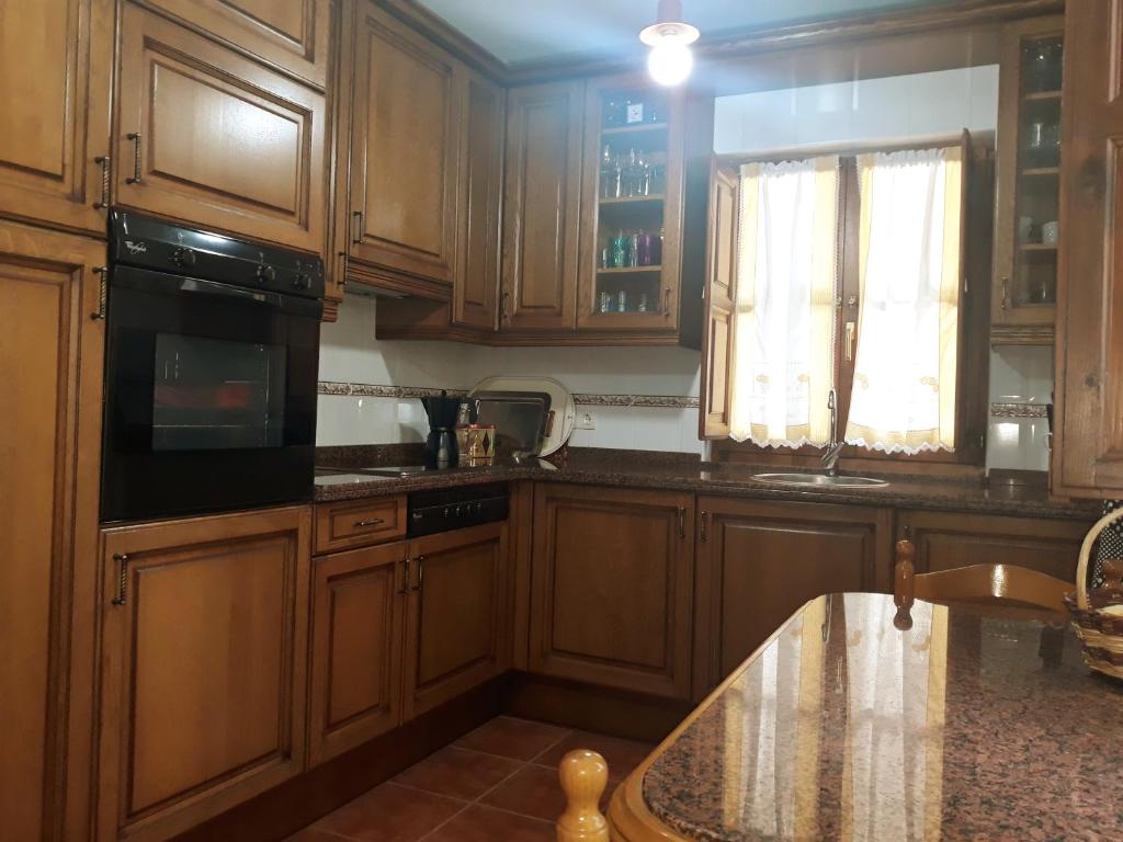 里瓦德塞利亚Casa Rural La Llosica的厨房配有木制橱柜、水槽和窗户。