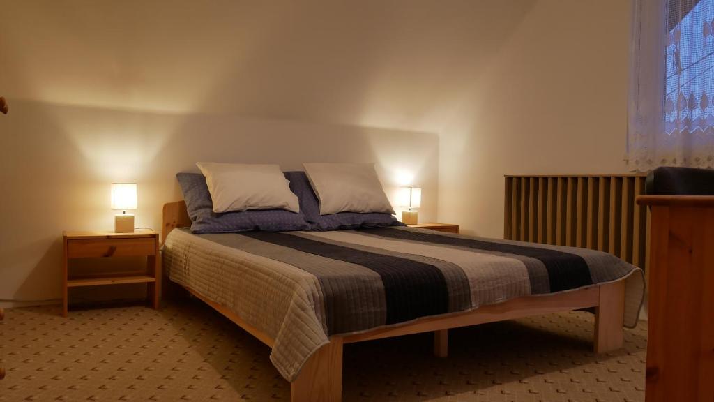 TerényHerőke Vendégház的一间卧室配有一张带2个床头柜和2盏灯的床。