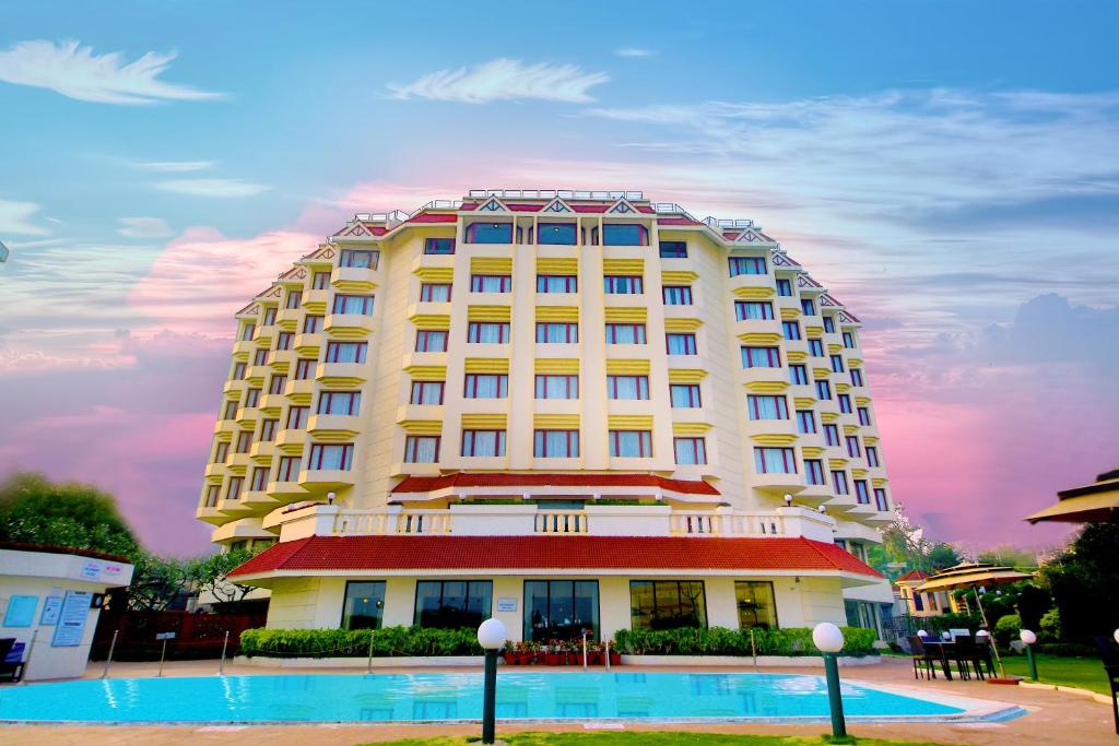 维沙卡帕特南Welcomhotel by ITC Hotels, Devee Grand Bay, Visakhapatnam的一座白色的大建筑,前面设有一个游泳池