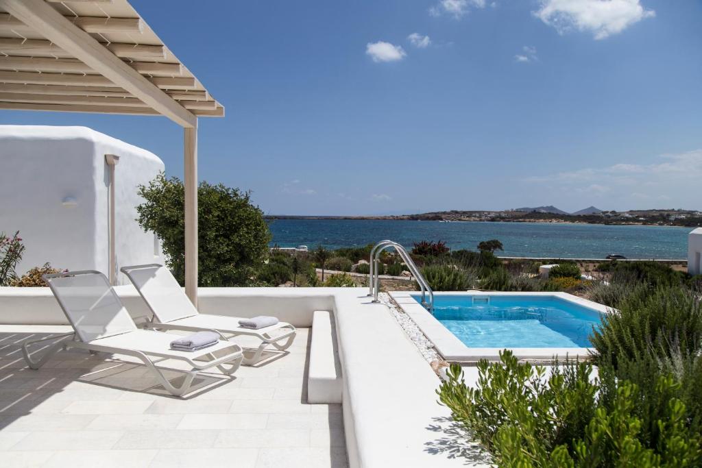 圣玛丽亚The Sand Collection Villas的一个带游泳池和椅子的庭院和大海