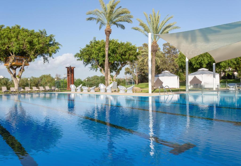 凯撒利亚Dan Caesarea Resort的一座棕榈树和白色帐篷的大型游泳池