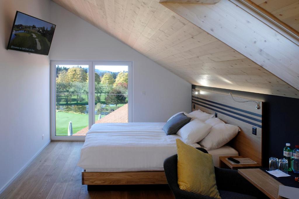 Les BoisHôtel Golf-Club Les Bois的一间卧室设有一张大床和一个大窗户