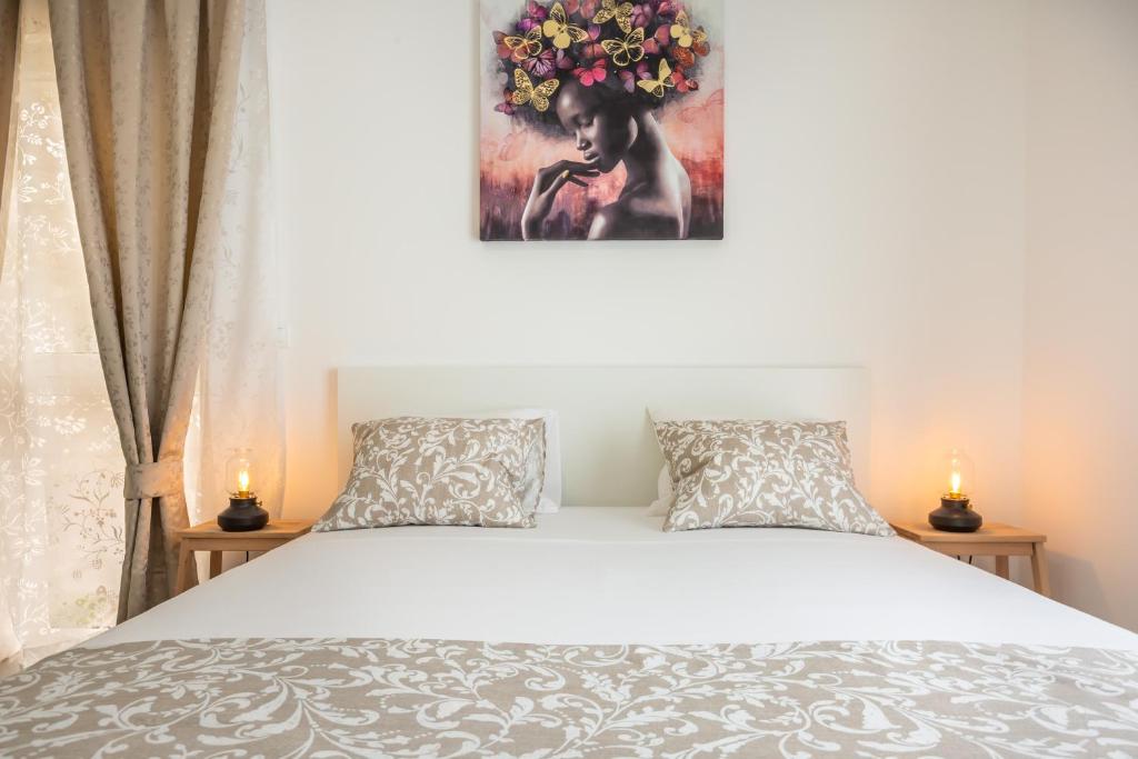 马卡尔斯卡Luxury apartments Nikolina Sea&City view的一间卧室配有带两个枕头的床和一幅画