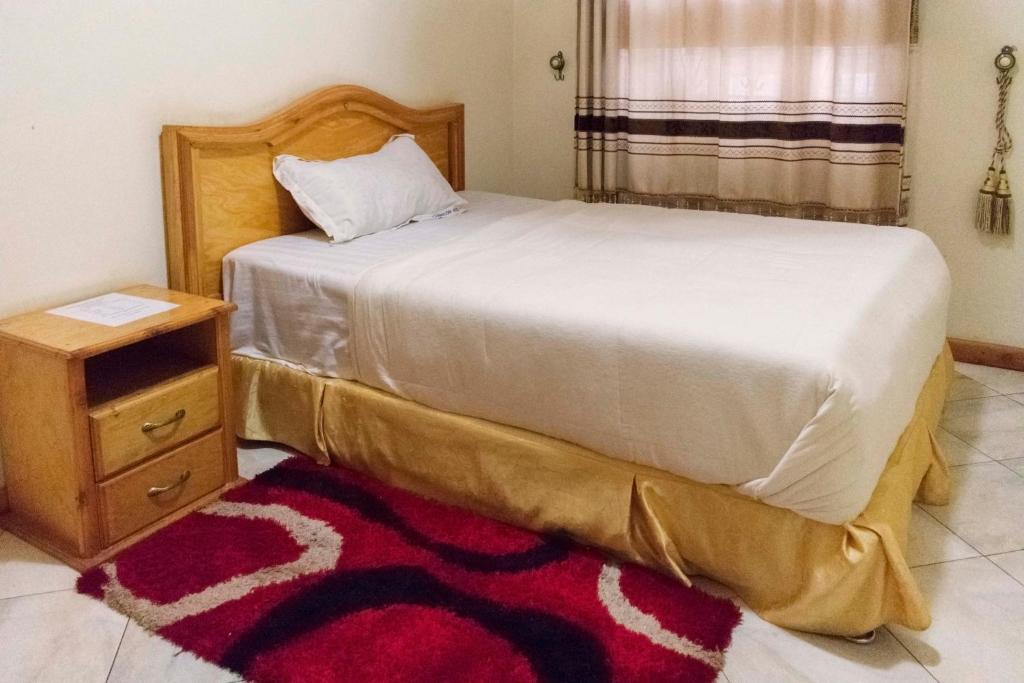 卡巴莱Capricon Executive Hotel Kabale的一间卧室配有床、床头柜和一张四柱床
