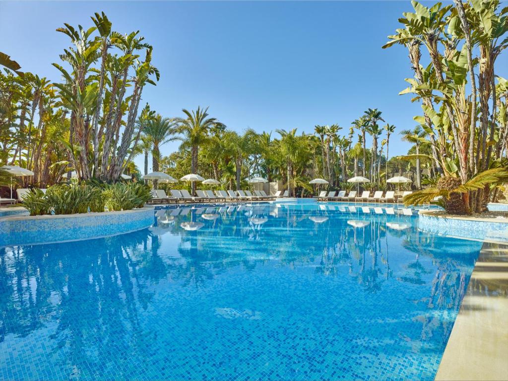 韦尔都勒博利雅公园Spa酒店的一座棕榈树和遮阳伞的大型游泳池