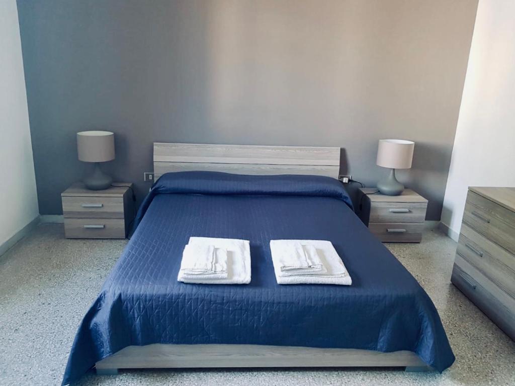 马蒂诺Appartamento Via del Mare的一间卧室配有蓝色的床、两张桌子和两条毛巾