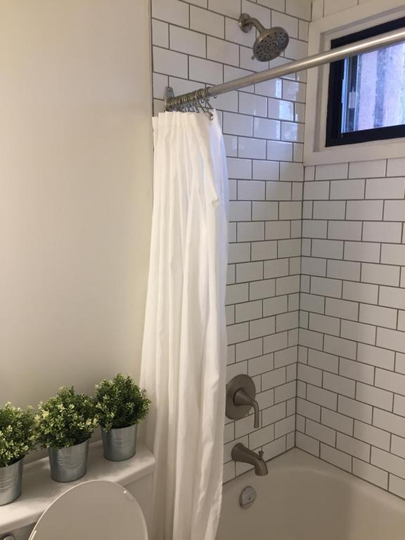 梅戈格Le Rustique Orford Domaine Cheribourg的浴室内有白色的窗帘,有植物