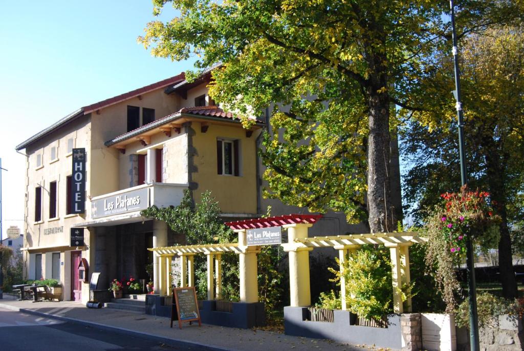Montfaucon-en-Velay普拉坦斯酒店餐厅的黄色的建筑,前面有标志
