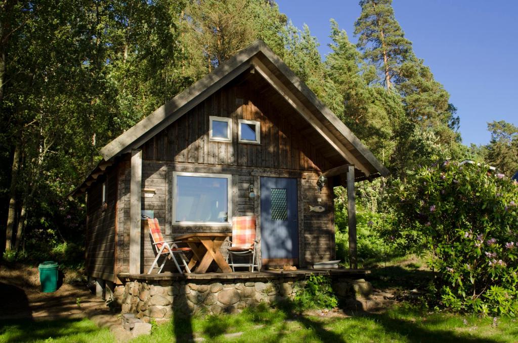 TämtaStrandstuga的树林中的小屋,配有一张桌子和两把椅子