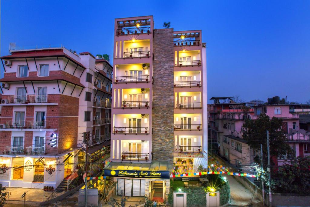 加德满都Kathmandu Suite Home的一座高大的白色建筑,晚上设有阳台