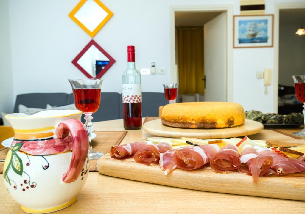 乌马格Apartment Dora的一张桌子,上面放有肉,还有一瓶葡萄酒和玻璃杯