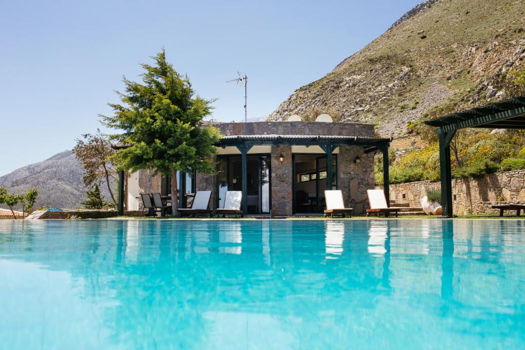 Krousón阿托维格拉旅馆的一个带椅子的游泳池和一个山间房子