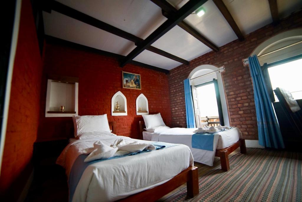 班迪普尔Bandipur chhen的一间卧室设有两张床和砖墙