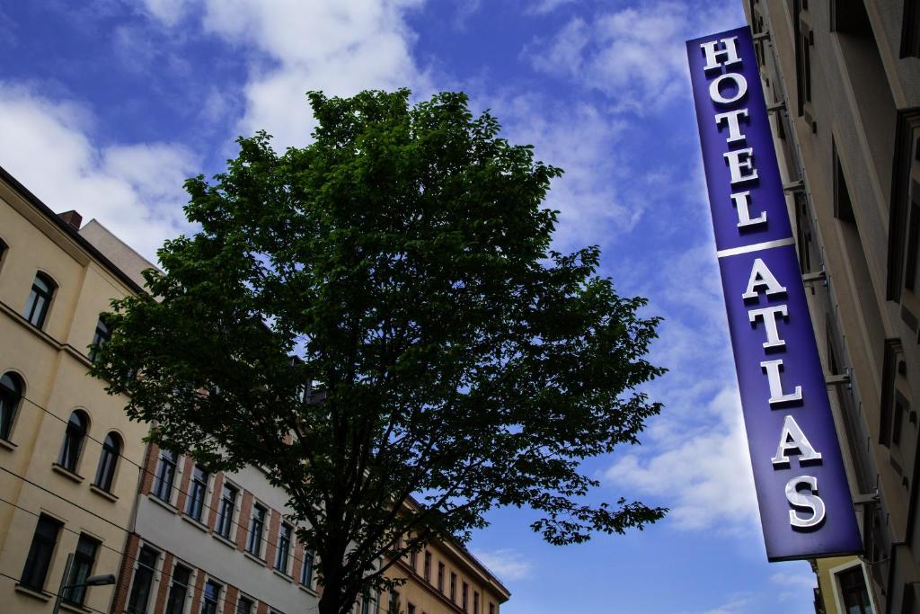 莱比锡Hotel Atlas Leipzig的前面有树的建筑物的标志