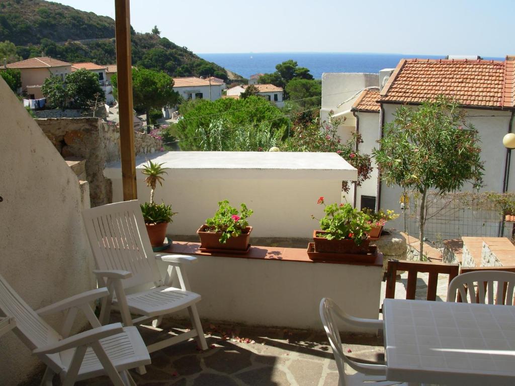 波蒙特Appartamento Il Nespolo的阳台的庭院配有白色椅子和盆栽植物