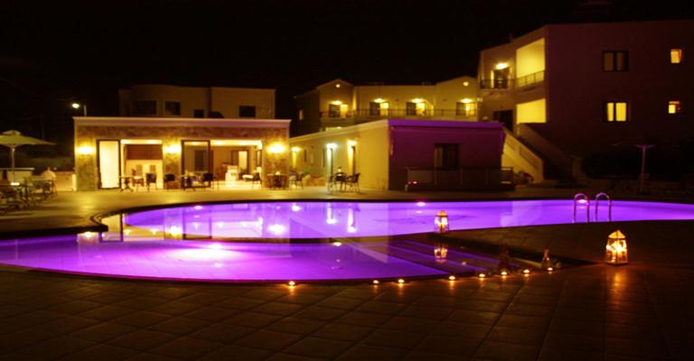卡拉马基Sandy Suites的游泳池晚上点亮紫色