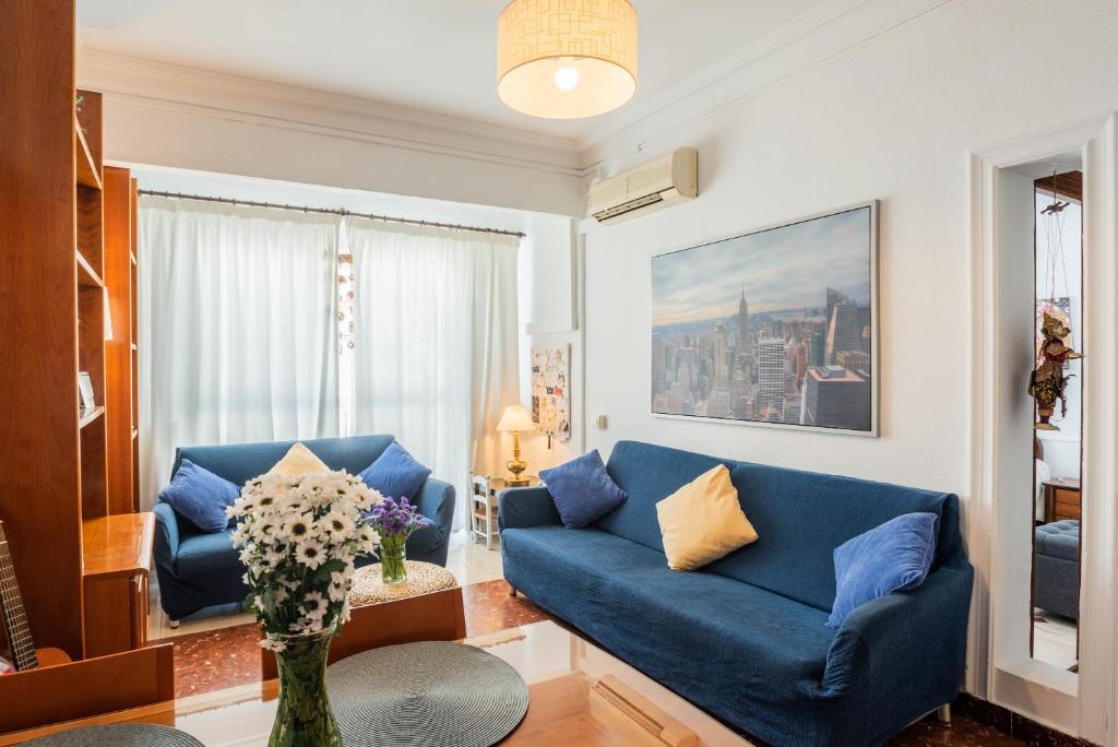 塞维利亚特里亚纳洛斯雷梅迪奥斯公寓的客厅设有蓝色的沙发和窗户。