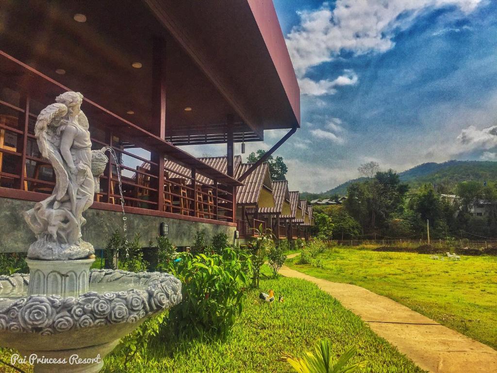 拜县Pai Princess Resort的坐在建筑物前面的草上的一个雕像