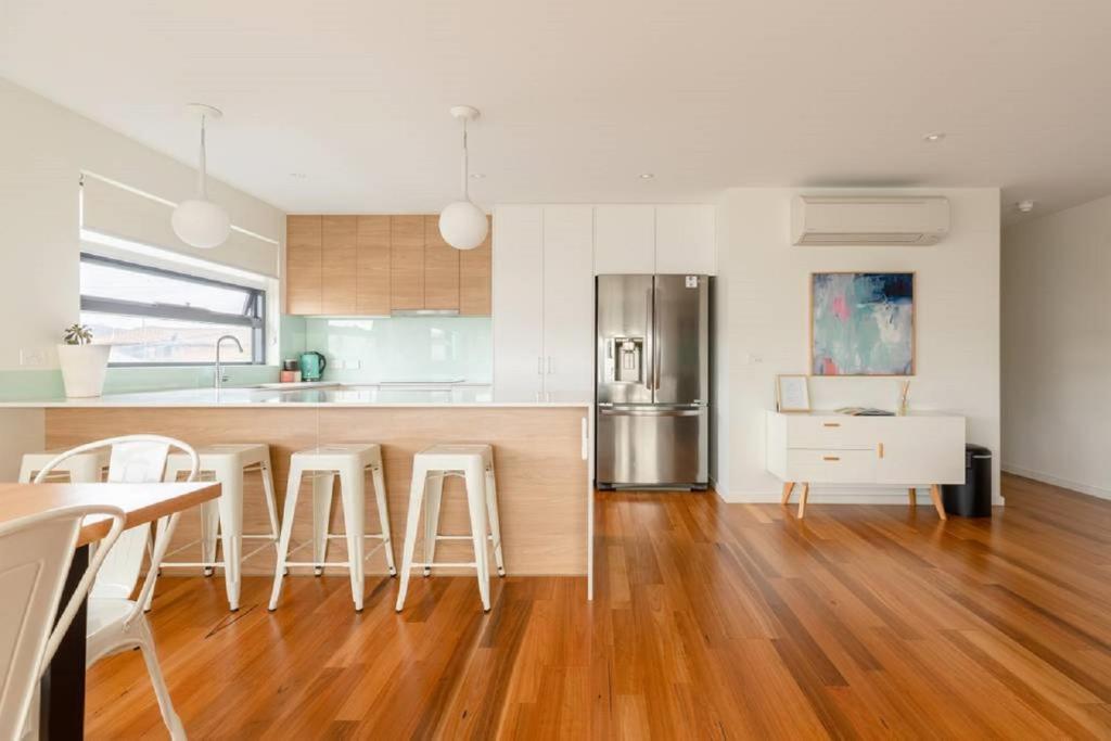 霍巴特袋鼠湾公寓的厨房铺有木地板,厨房配有凳子。