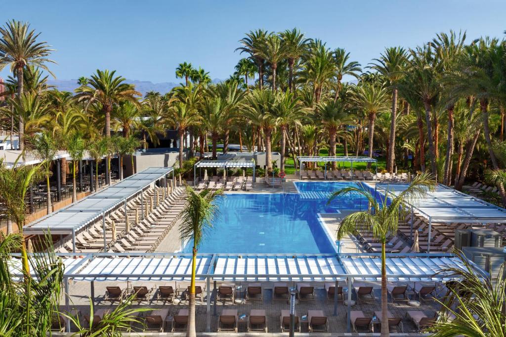马斯帕洛马斯Hotel Riu Palace Oasis的棕榈树度假村泳池的空中景致