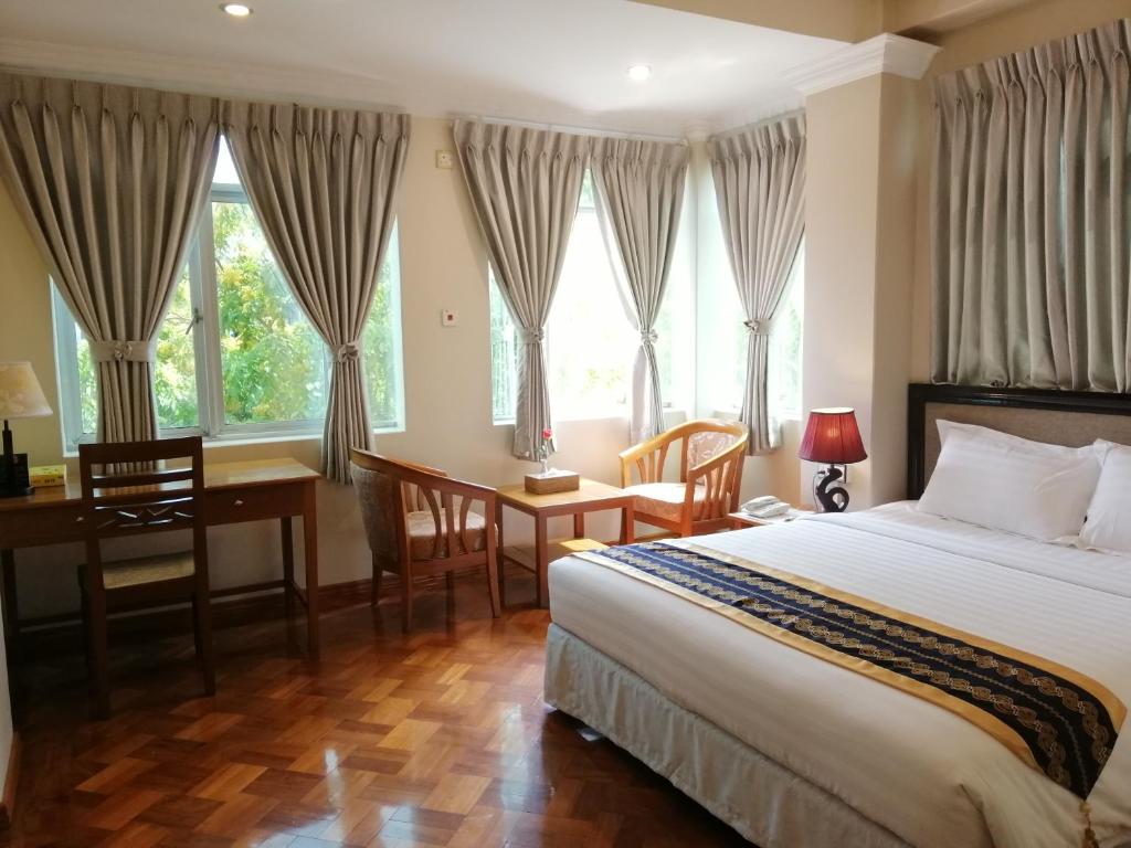 仰光格兰德桂冠酒店的卧室配有一张床、一张书桌和窗户。