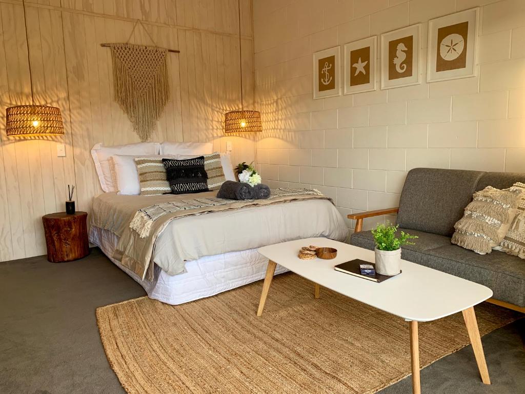 凯库拉Kaikōura Peaks eMotel的一间卧室配有一张床、一张沙发和一张桌子