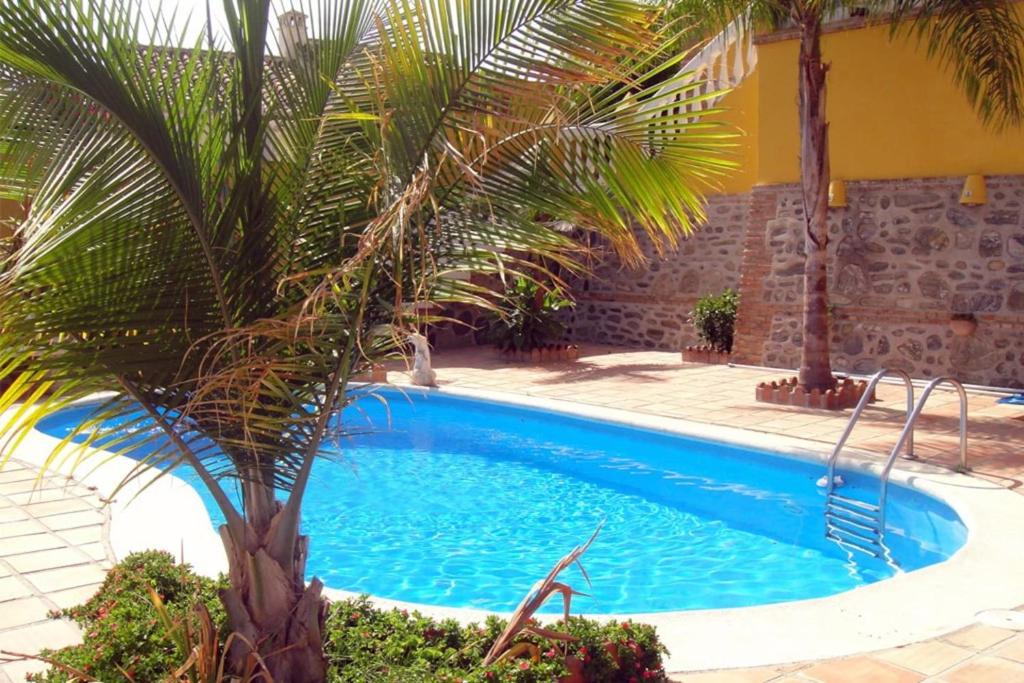阿尔姆尼卡CHALET CON PISCINAS Y VISTAS DE ENSUEÑO的一座棕榈树游泳池,毗邻一座建筑