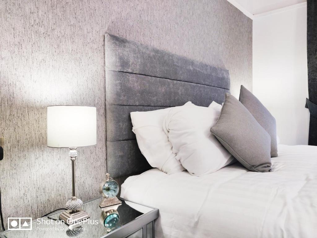 伦敦德里意外之喜别墅酒店的一间卧室配有带白色枕头和灯的床