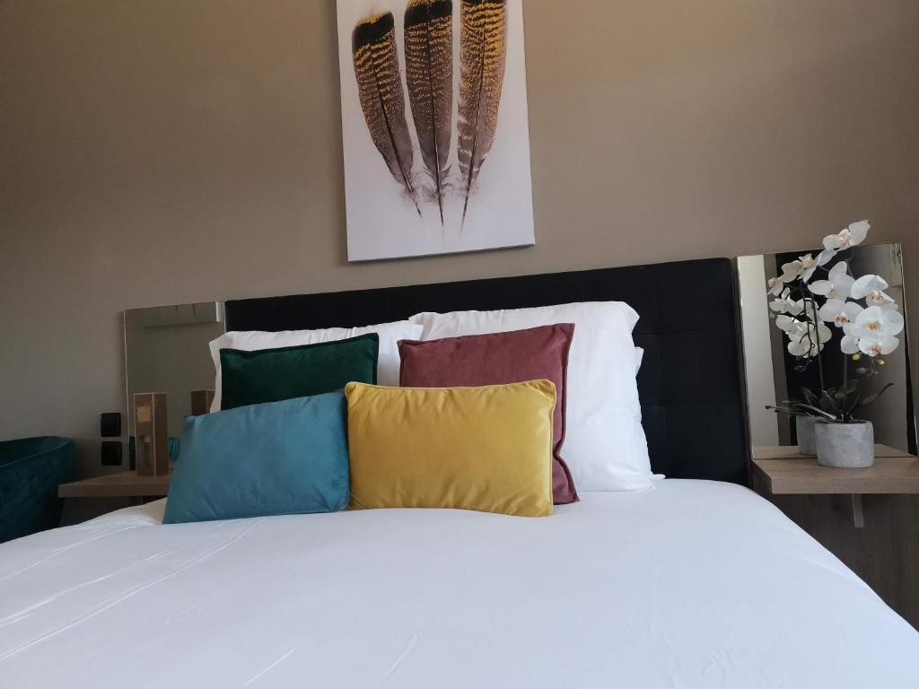 朗贡Home Place Apartments - Langon Sauternes的卧室配有白色的床和色彩缤纷的枕头