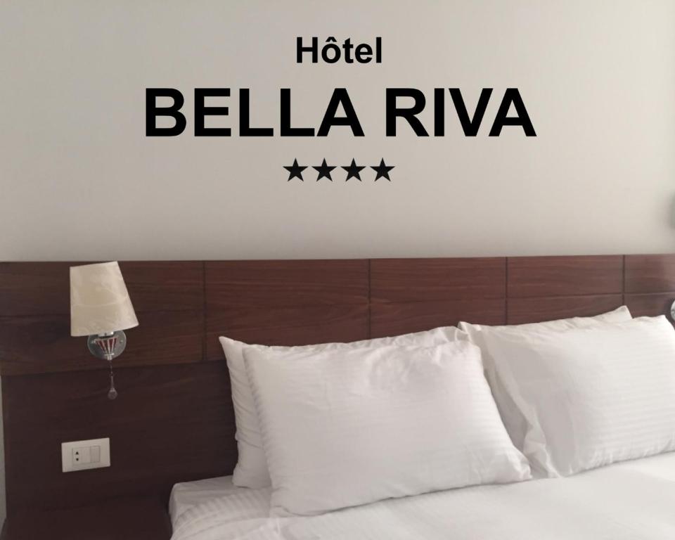 金沙萨Hotel Bella Riva Kinshasa的卧室配有一张床铺,墙上挂着酒店红花标志