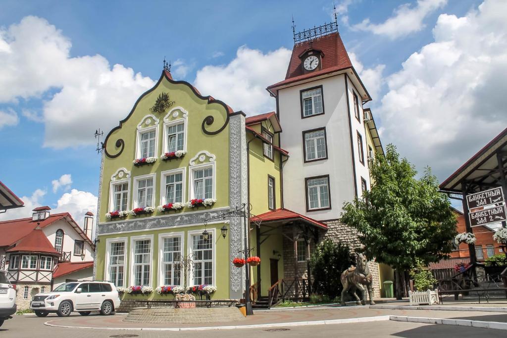 梁赞康裕施尼德沃尔旅馆的一座黄色和白色的建筑,设有钟楼
