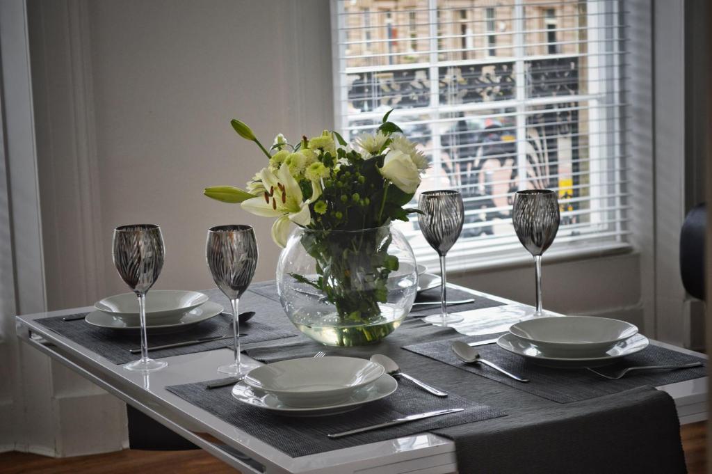 伯肯黑德Apartment 4 Hamilton Square的一张桌子,上面有盘子和玻璃杯,花瓶