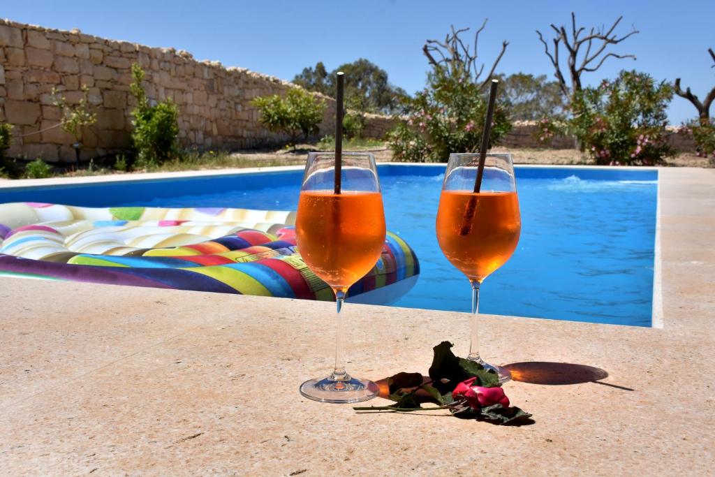 比尔泽布贾Four Winds Farmhouse的两个香槟杯坐在游泳池旁的桌子上