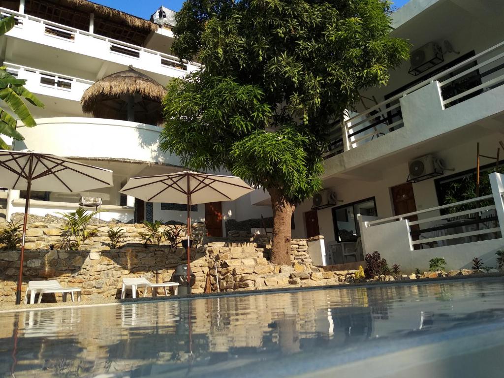 波尔多·格尼拉Jalyn's Resort Sabang的一个带遮阳伞的游泳池和一座建筑