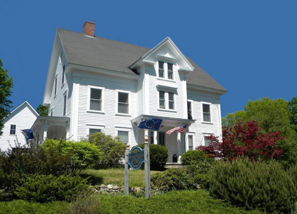 AndoverHighland Lake Inn的前面有旗帜的白色房子