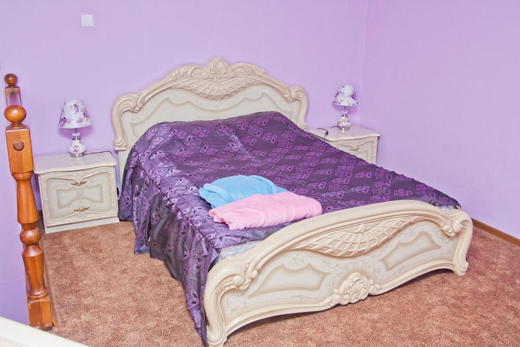 赤塔大城市酒店的一间卧室配有一张带紫色床单和枕头的床。