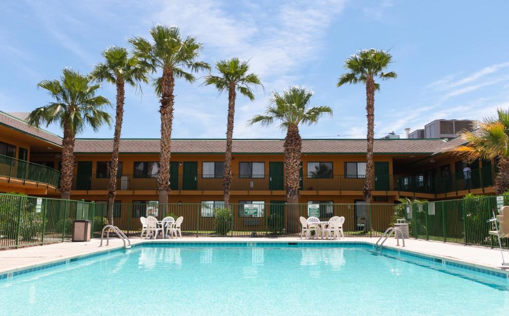 优马Budgetel Inn & Suites的酒店前方的棕榈树游泳池