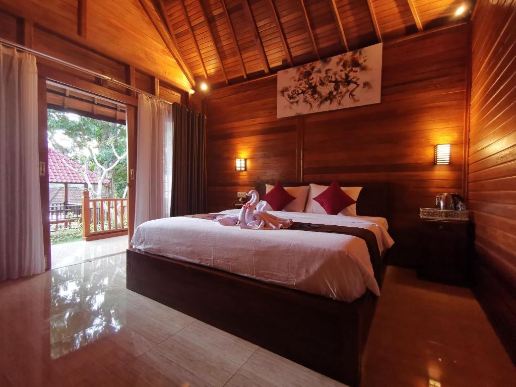 珀尼达岛Kamasan Cottage的木制客房内的一间卧室配有一张大床
