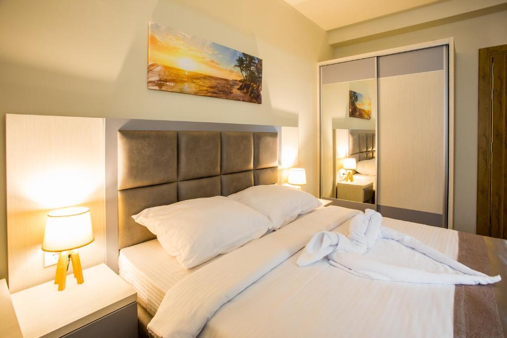 赫尔采格诺维Hotel Olimpija plus的一间卧室配有一张带两盏灯的大型白色床。