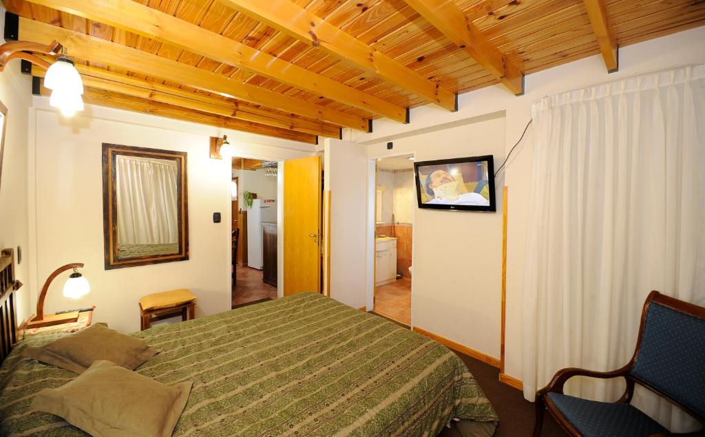 圣卡洛斯-德巴里洛切南桥宾馆的卧室配有一张床,墙上配有电视。