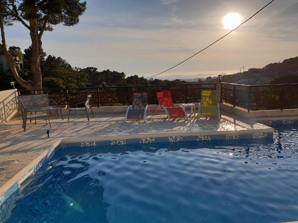 马赛Studio d'environ 20m2, piscine, vue mer, pour 2 personnes的一个带椅子和桌子的游泳池,阳光充足