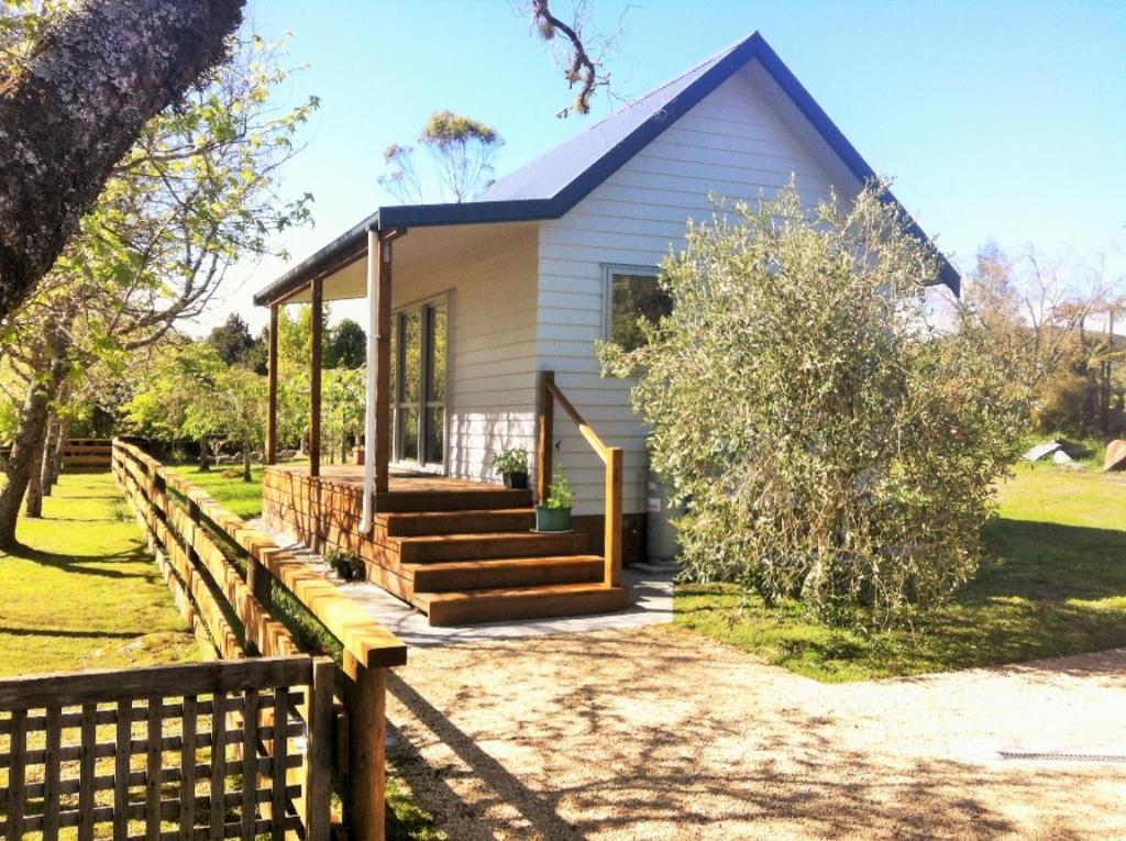 RuatapuMirror Creek Holiday Cottage的白色的小房子,设有木栅栏