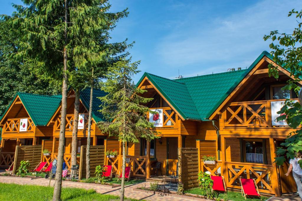 斯图托沃Domki pod lasem blisko morza的前面的木制房屋,配有红色椅子